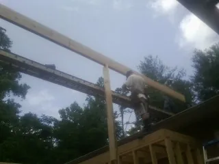 Carpenter setting a ridge beam over a new addition frame — Ice Dam Removal by Roofing Brothers in Gretna