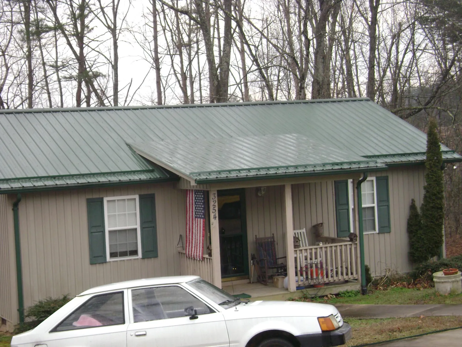 Green metal roof and front porch on a tan sided cottage in Gretna