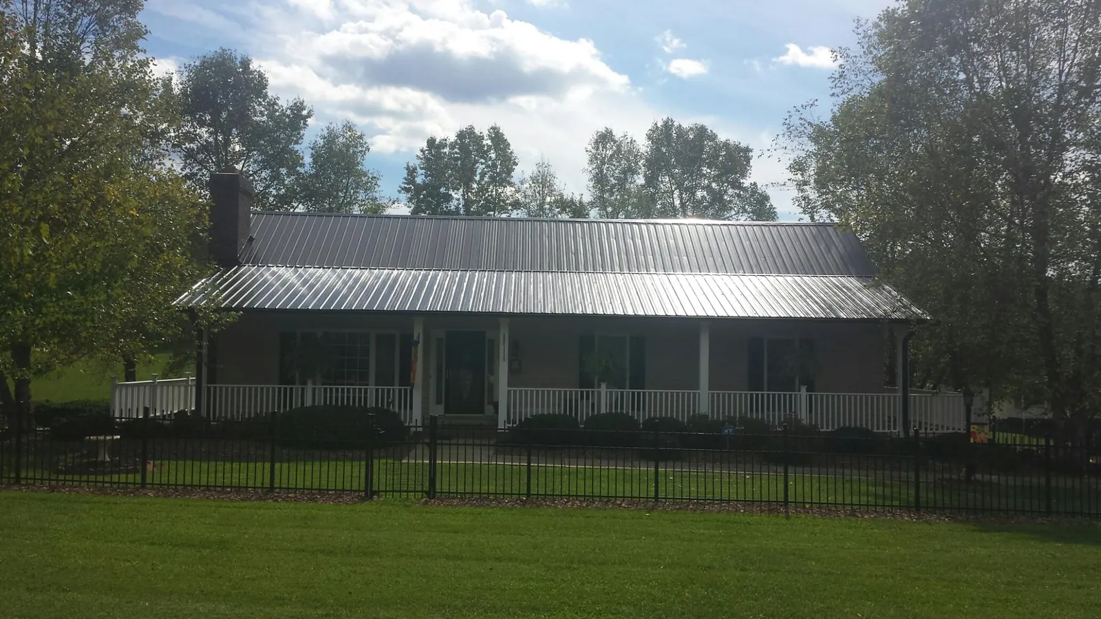 Gray metal roof on a brick ranch with a full width front porch — Gutter Guard Installation work by our crew in Gretna