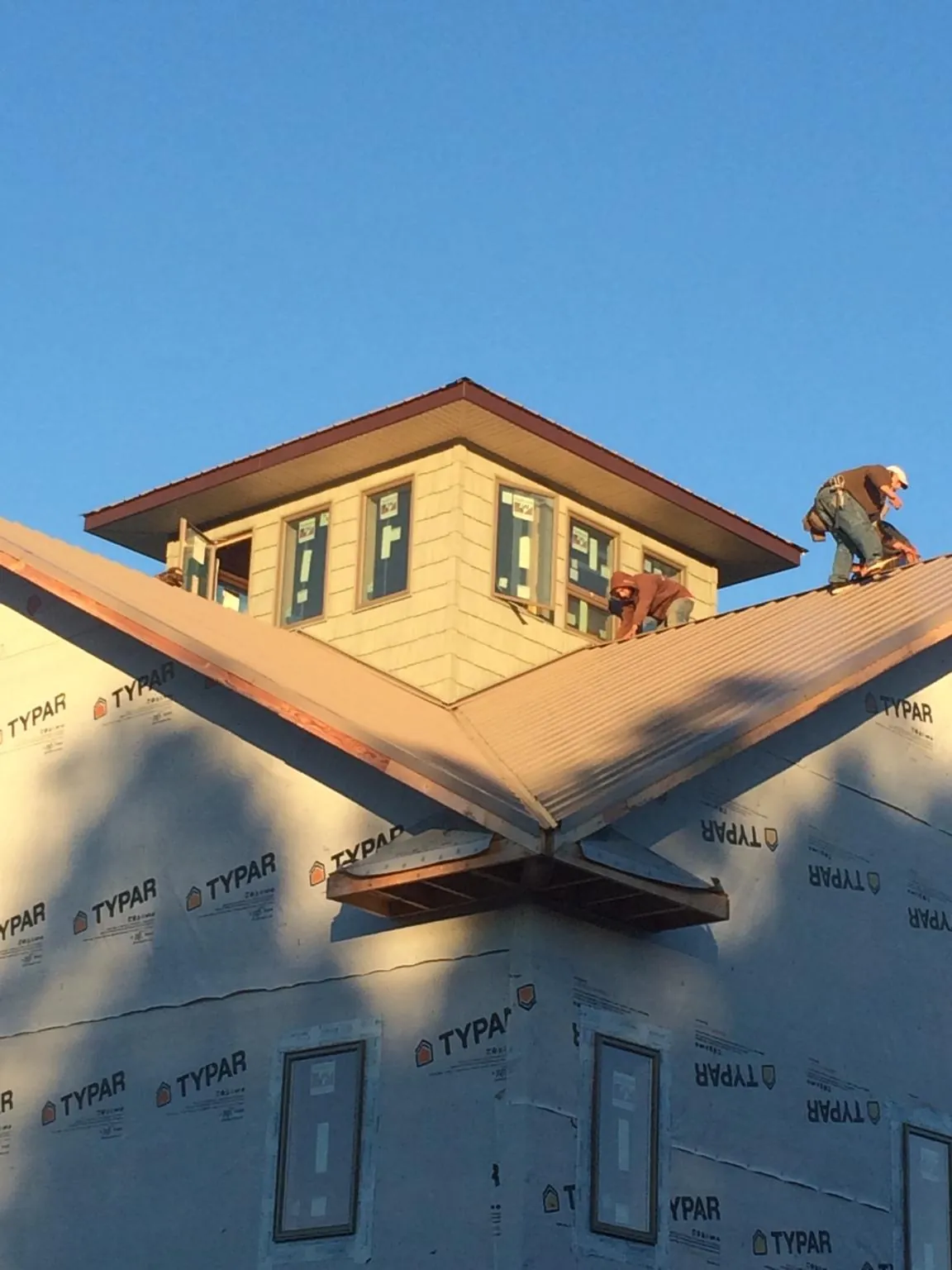 Roofers working around a rooftop cupola on a new metal roof at sunset — Roof Waterproofing in Gretna by Roofing Brothers